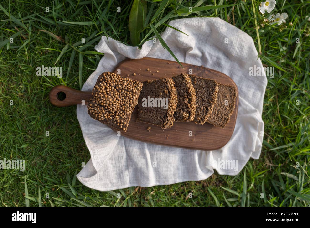 Composizione del pane casereccio su tavola di legno con tovagliolo bianco sull'erba verde. Foto di alta qualità Foto Stock