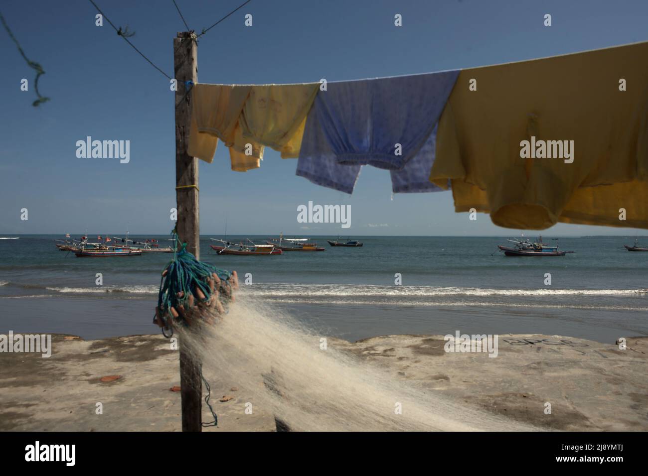 Lavanderia e rete da pesca in uno sfondo di barche da pesca e Oceano Indiano, fotografato sulla spiaggia Malabero (Malabro) in Bengkulu, Indonesia. Foto Stock