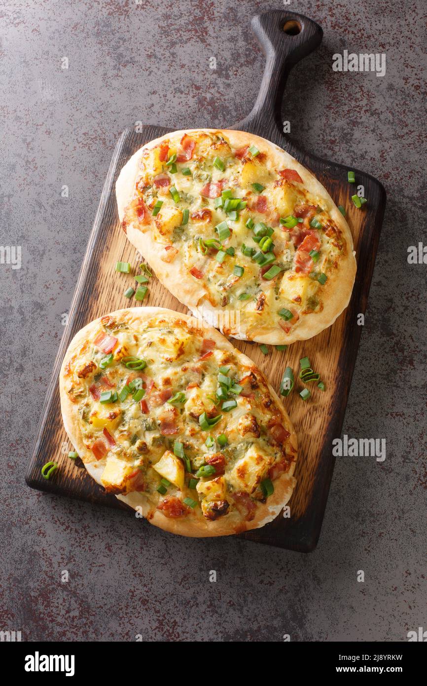 Il Dinnete è un piatto tradizionale tedesco originario del Baden-Wurttemberg, con panna acida, patate, cipolle, prosciutto e formaggio da vicino su un woo Foto Stock