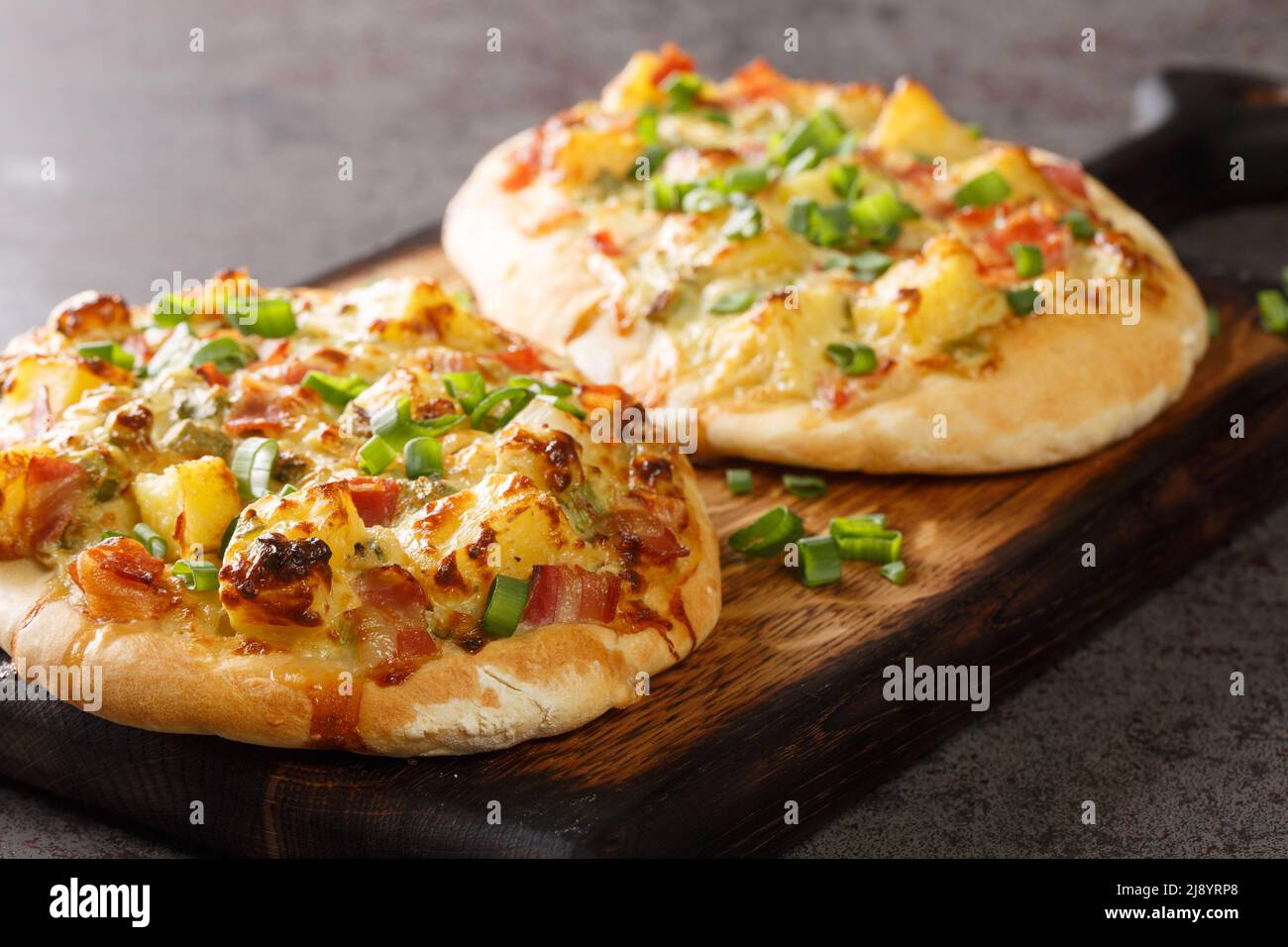 Aprire la torta con formaggio, patate, cipolle e pancetta da vicino su un asse di legno sul tavolo. Orizzontale Foto Stock