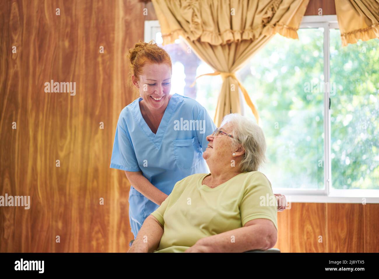 Infermiera geriatrica in conversazione con un anziano in una casa di cura o in una struttura di vita assistita Foto Stock