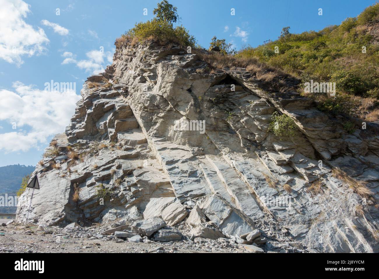 Una collina rocciosa tagliata in giù sulla strada per l'allargamento della strada nello stato di Uttarakhand in India. Foto Stock