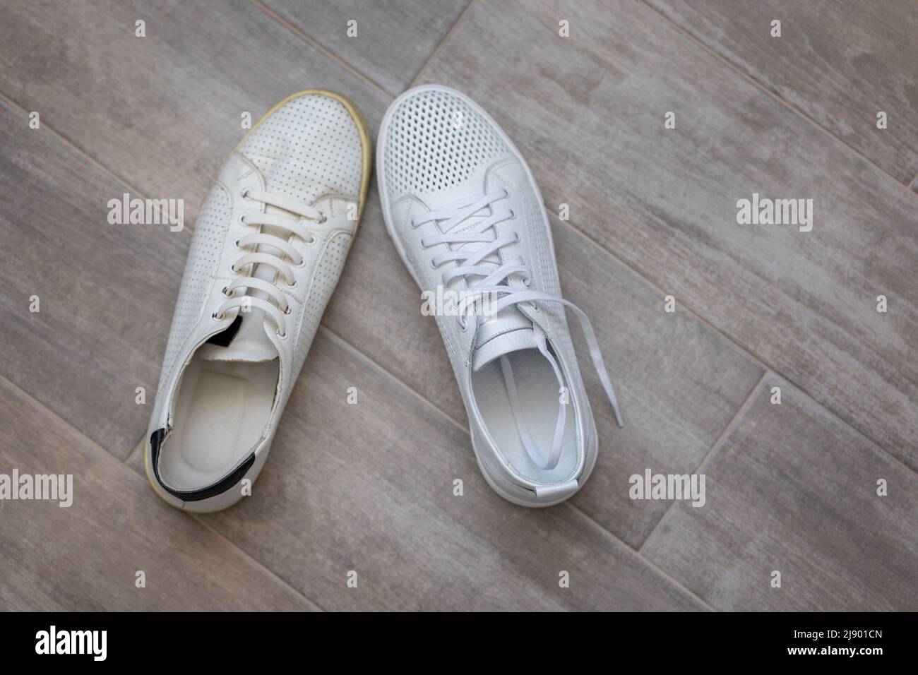 Coppia di scarpe alla moda bianche vecchie e nuove su sfondo di legno chiaro, vista dall'alto. Foto di alta qualità Foto Stock