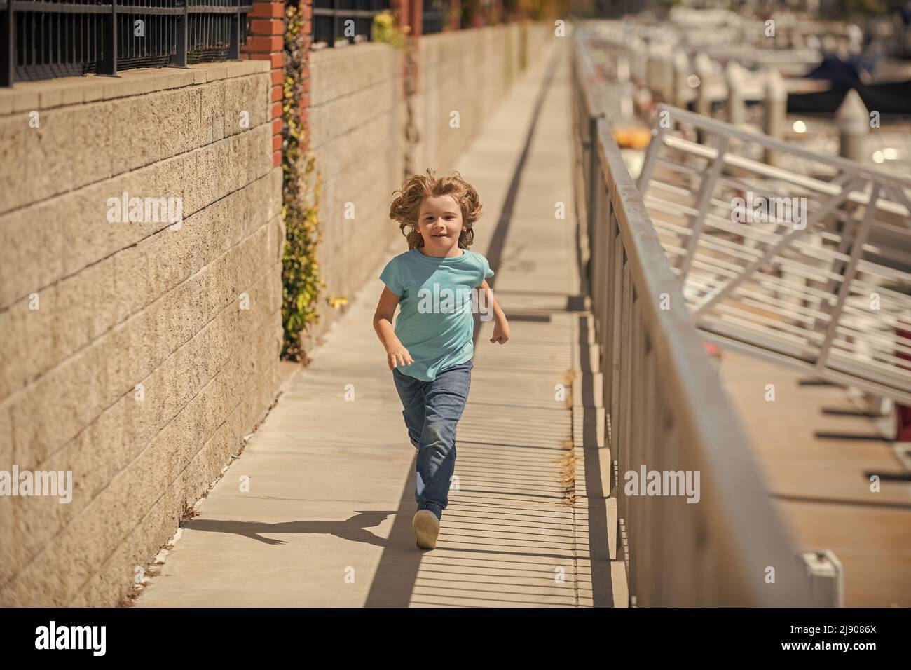 Bambino ragazzo attivo divertirsi a correre sul lungomare in estate, attività Foto Stock