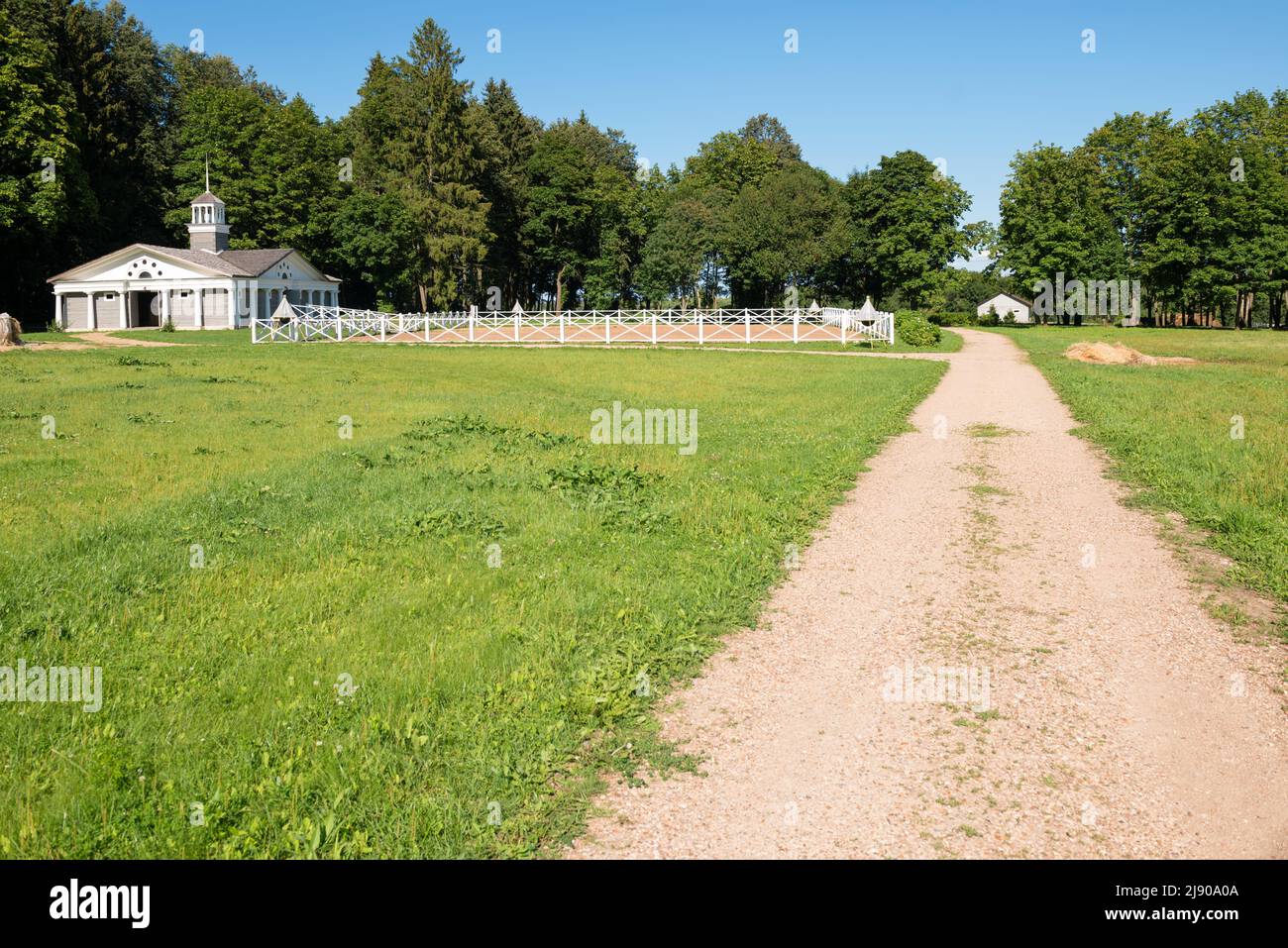 Corral in legno per il dressage dei cavalli in campagna in una giornata di sole. Paddock su terreno agricolo con recinzione in legno Foto Stock
