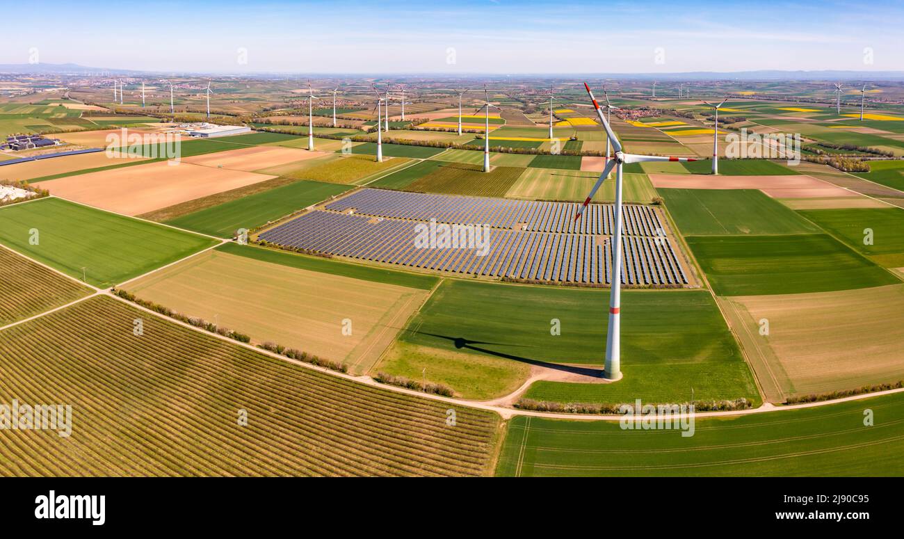 Enormi turbine eoliche tra terreno agricolo e parco solare in una zona rurale da una vista con droni, la Germania Foto Stock