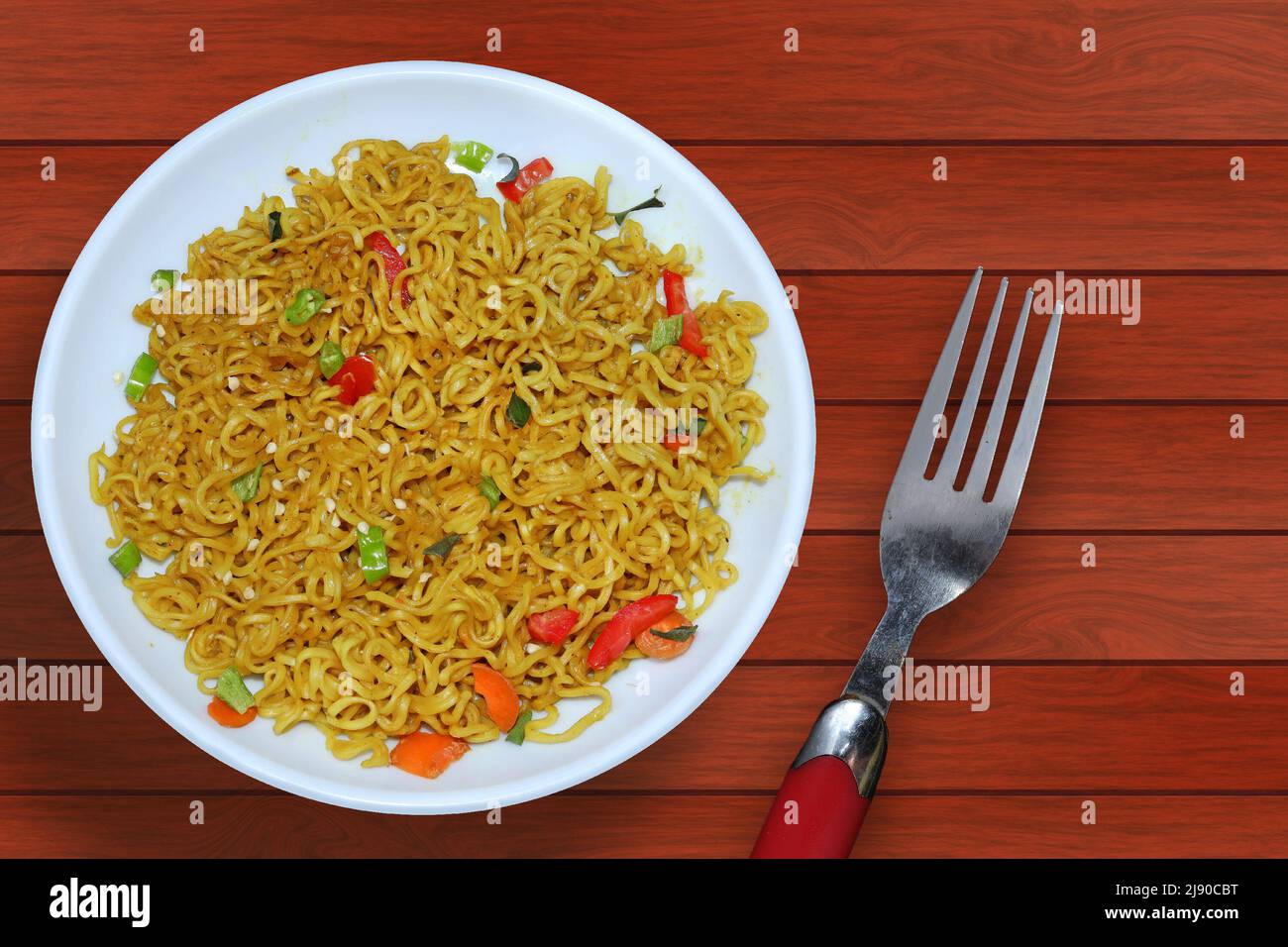 Vista dall'alto spaghetti istantanei su un piatto bianco su uno sfondo di legno Foto Stock