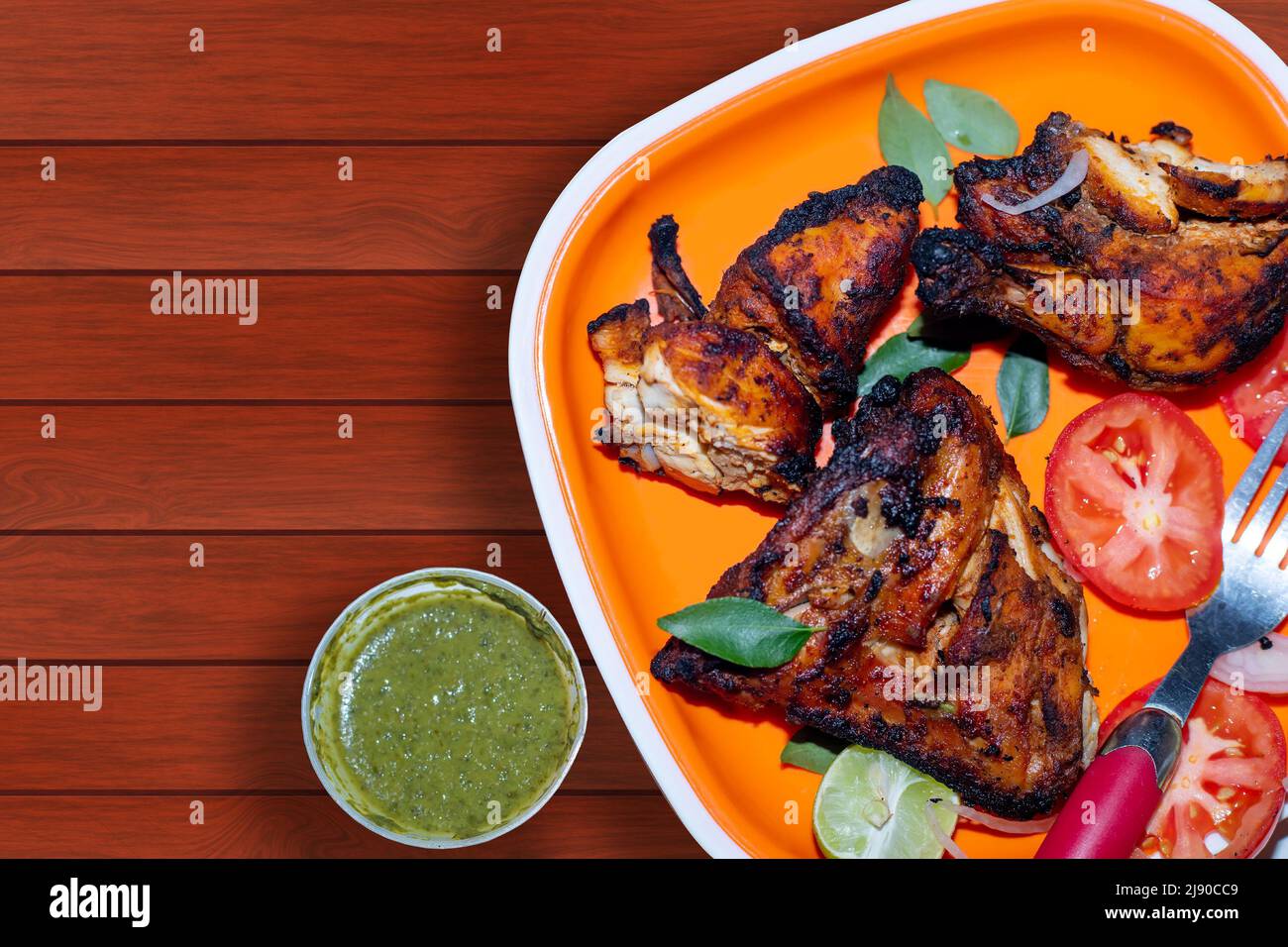 Un pollo tandoori alla griglia fatto in casa servito con insalate e chutney di menta coriandolo. Foto Stock