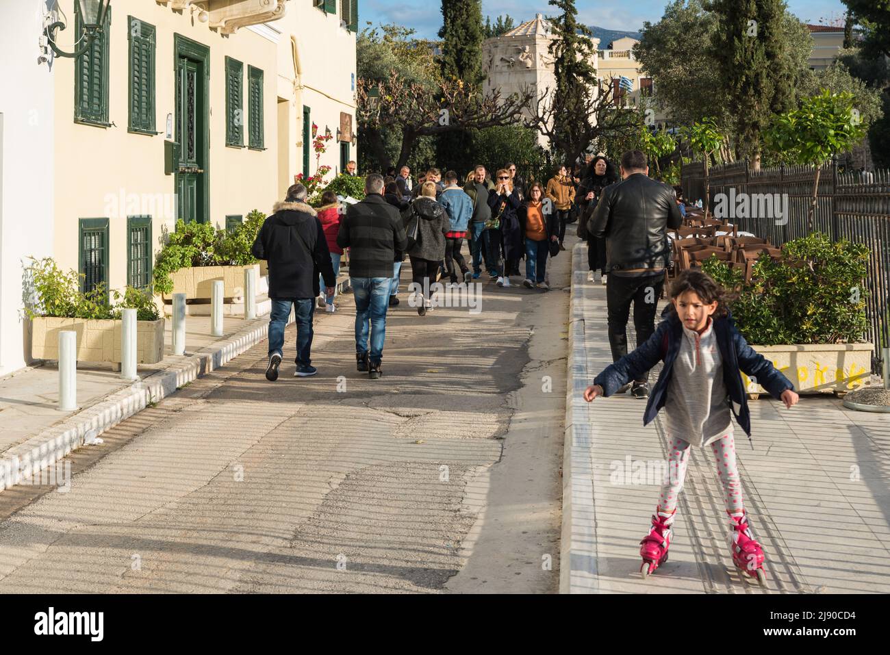 Città vecchia di Atene, Attica, Grecia - 12 28 2019 Kid sulle lame del rullo e la gente che cammina attraverso le strade della città vecchia intorno all'Acropoli Foto Stock