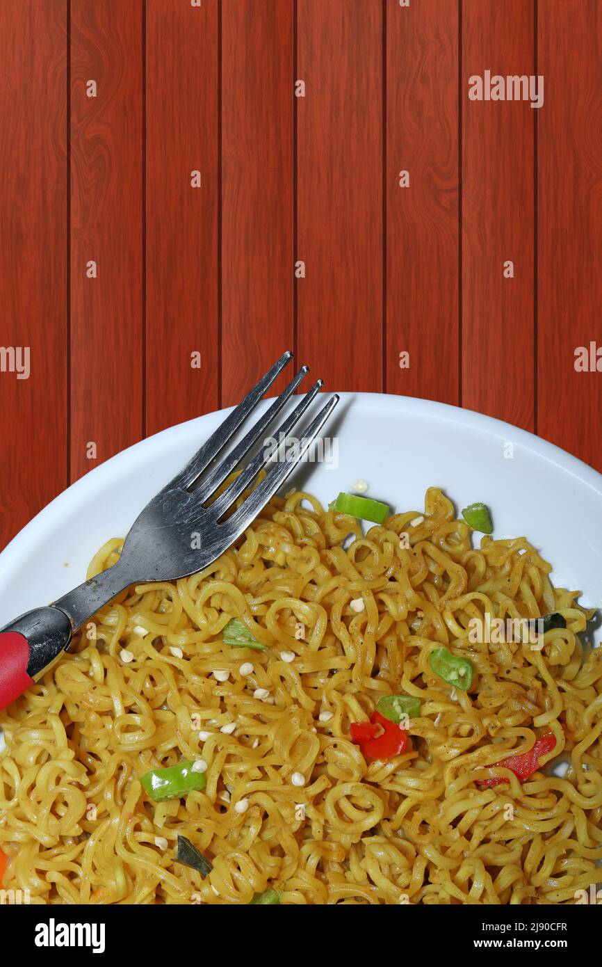 Vista dall'alto di spaghetti istantanei su un piatto bianco contro uno sfondo di tavolo in legno Foto Stock