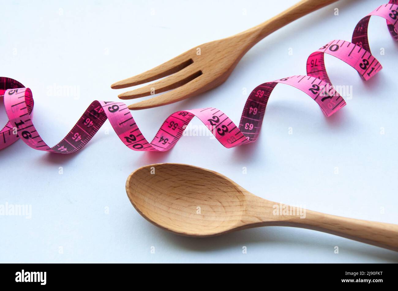 Rubinetto di misurazione con cucchiaio di legno e forchetta su sfondo bianco. Concetto di perdita di peso Foto Stock