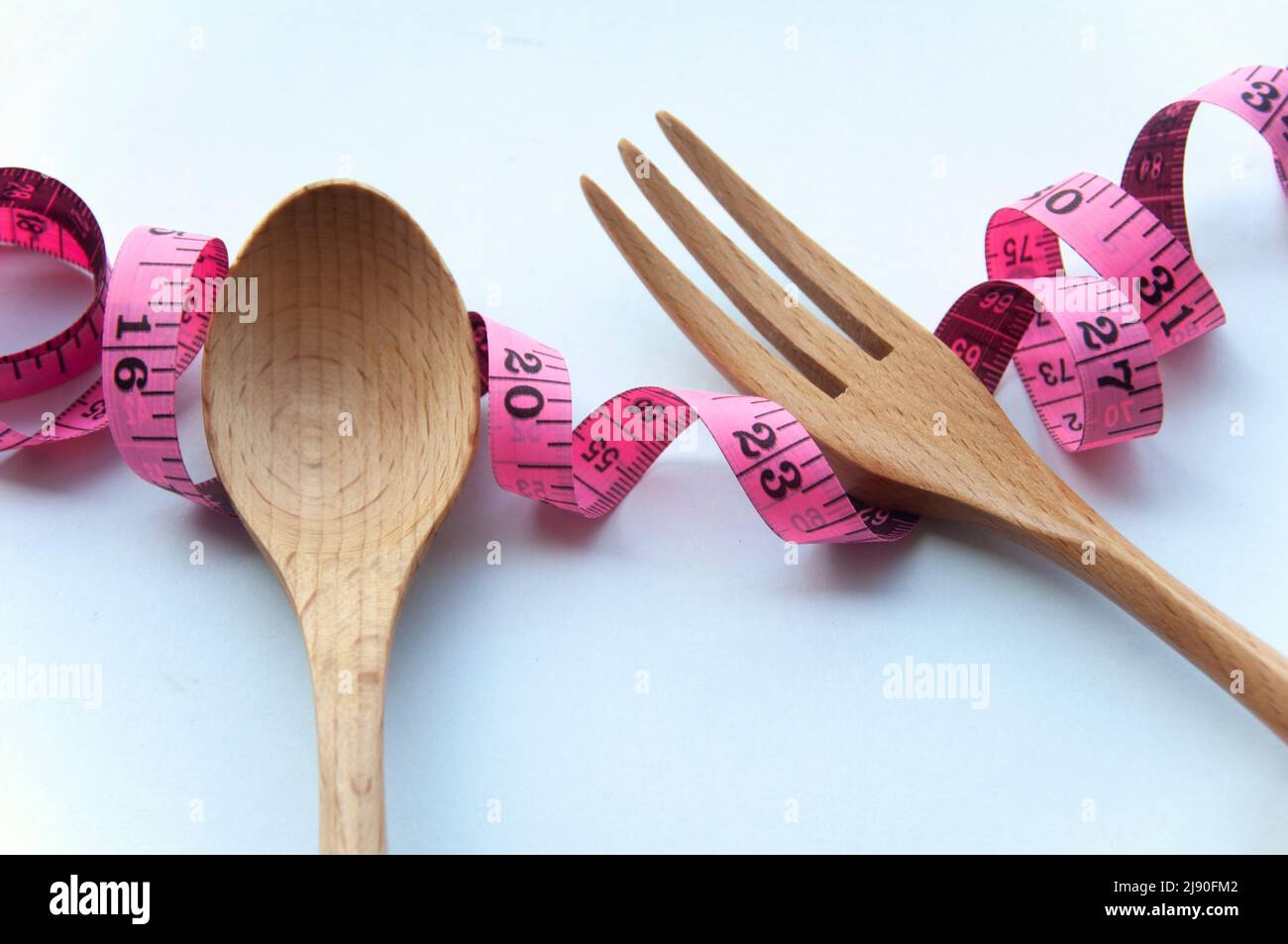 Rubinetto di misurazione con cucchiaio di legno e forchetta su sfondo bianco. Concetto di perdita di peso Foto Stock