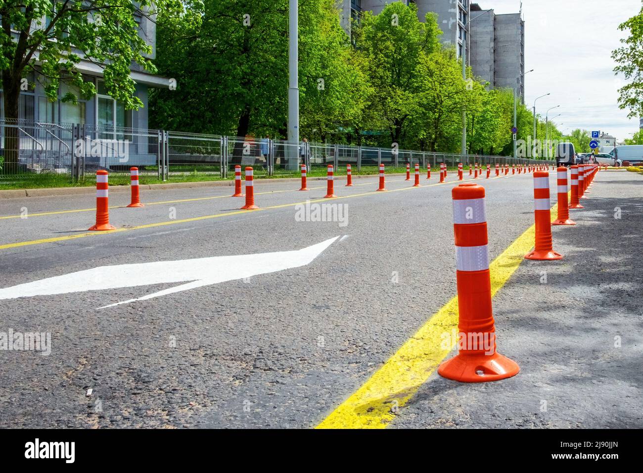 Pali di colore arancione sulla strada. I pali in plastica per dividere le corsie sono allineati su strada Foto Stock