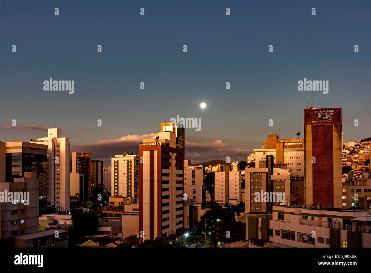 Città di Belo Horizonte, nella regione sud-orientale del Brasile, vista al crepuscolo con la luna piena sopra gli edifici, Foto Stock