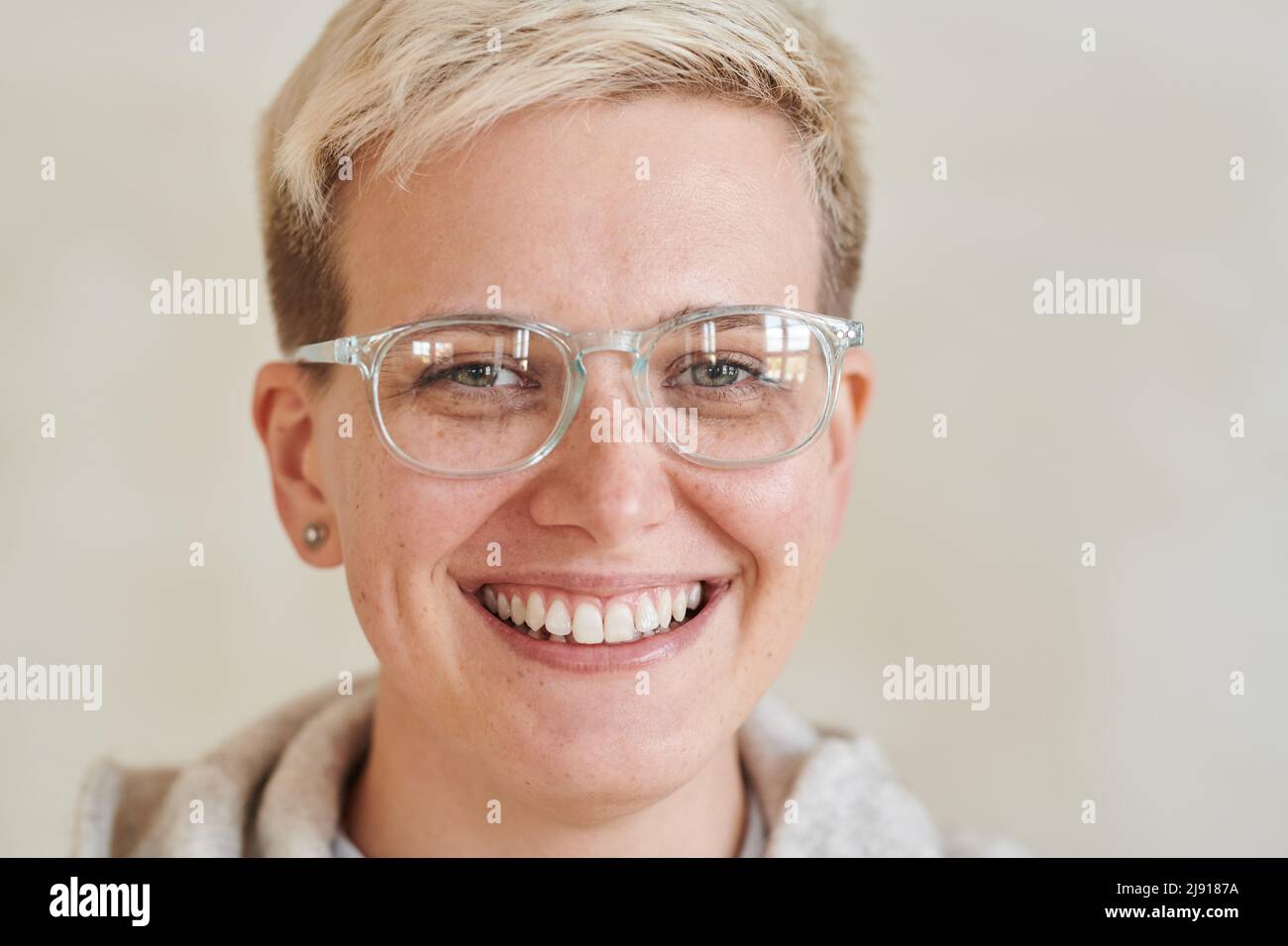 Ritratto di bella ragazza tomboy positivo con capelli biondi corti indossando occhiali su sfondo isolato Foto Stock