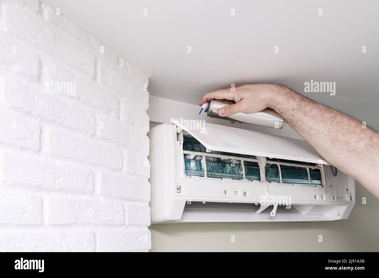 master man lavando l'unità interna di un condizionatore d'aria domestico  con una schiuma speciale di pulizia Foto stock - Alamy