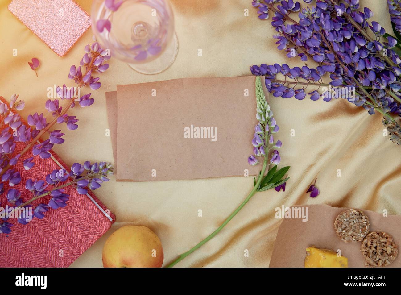 Carta artigianale mock up. Invito femminile estivo, biglietto di compleanno, concetto di festa della mamma. Lupini fiori viola, mela e biscotti decorazioni. Vibrant ba Foto Stock