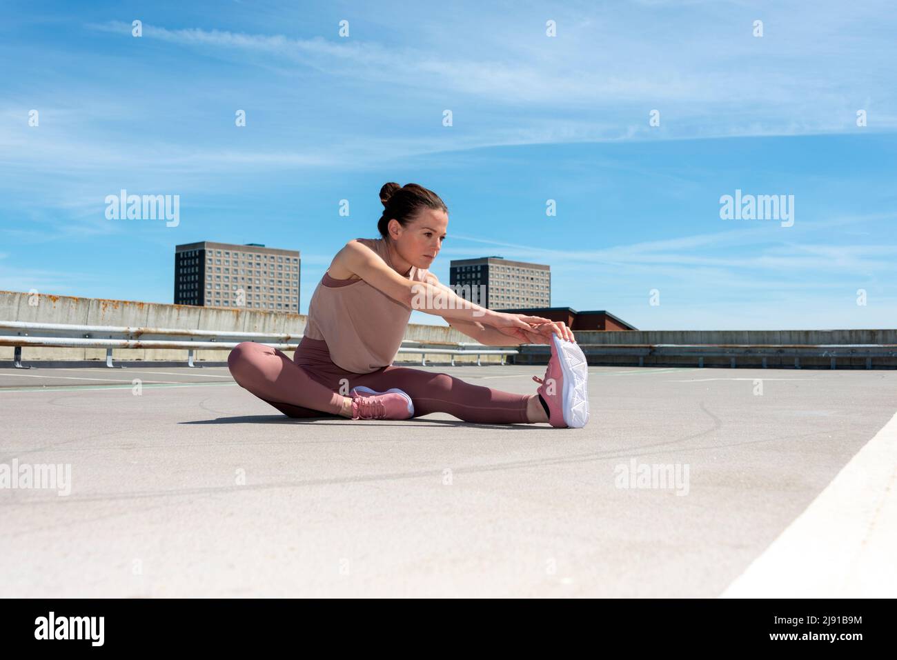Donna sportiva che fa una gamba stretch riscaldamento esercizio fuori, ambiente urbano. Foto Stock