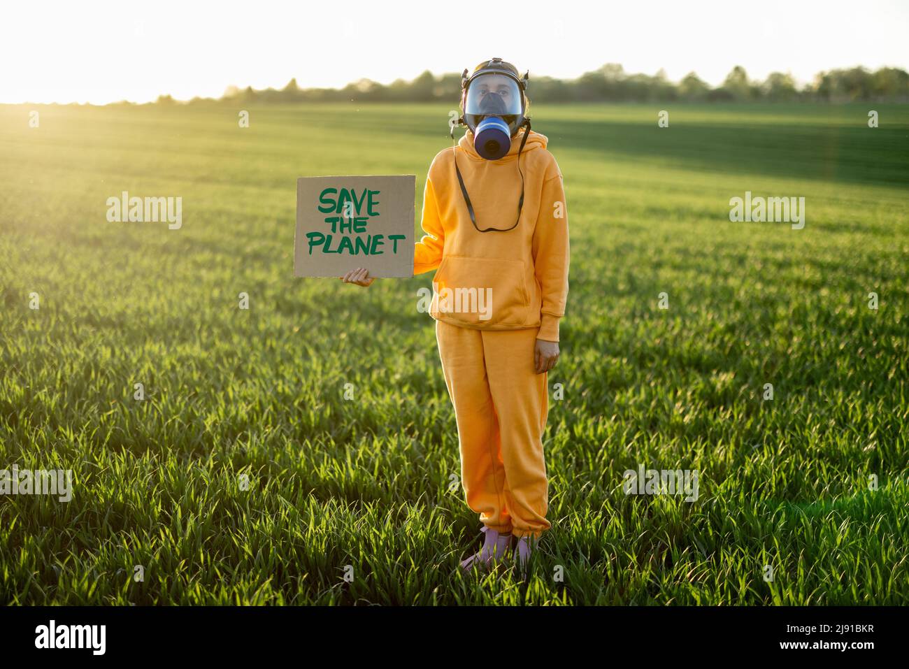 La persona in maschera a gas trattiene il cartone con una chiamata per salvare il pianeta Foto Stock