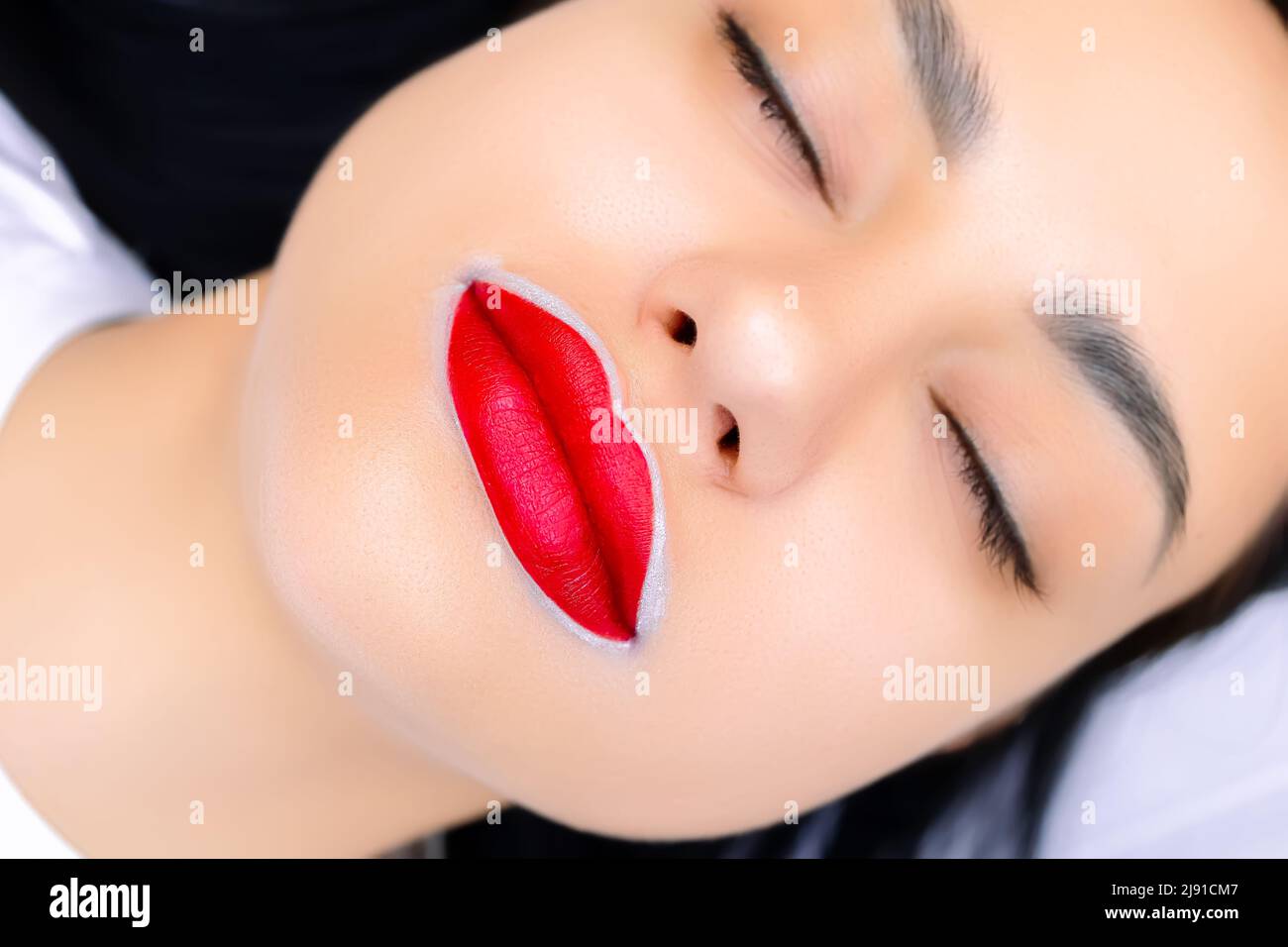 macro fotografia delle labbra di un modello preparato per una procedura permanente di trucco con il rosso applicato ad esse Foto Stock