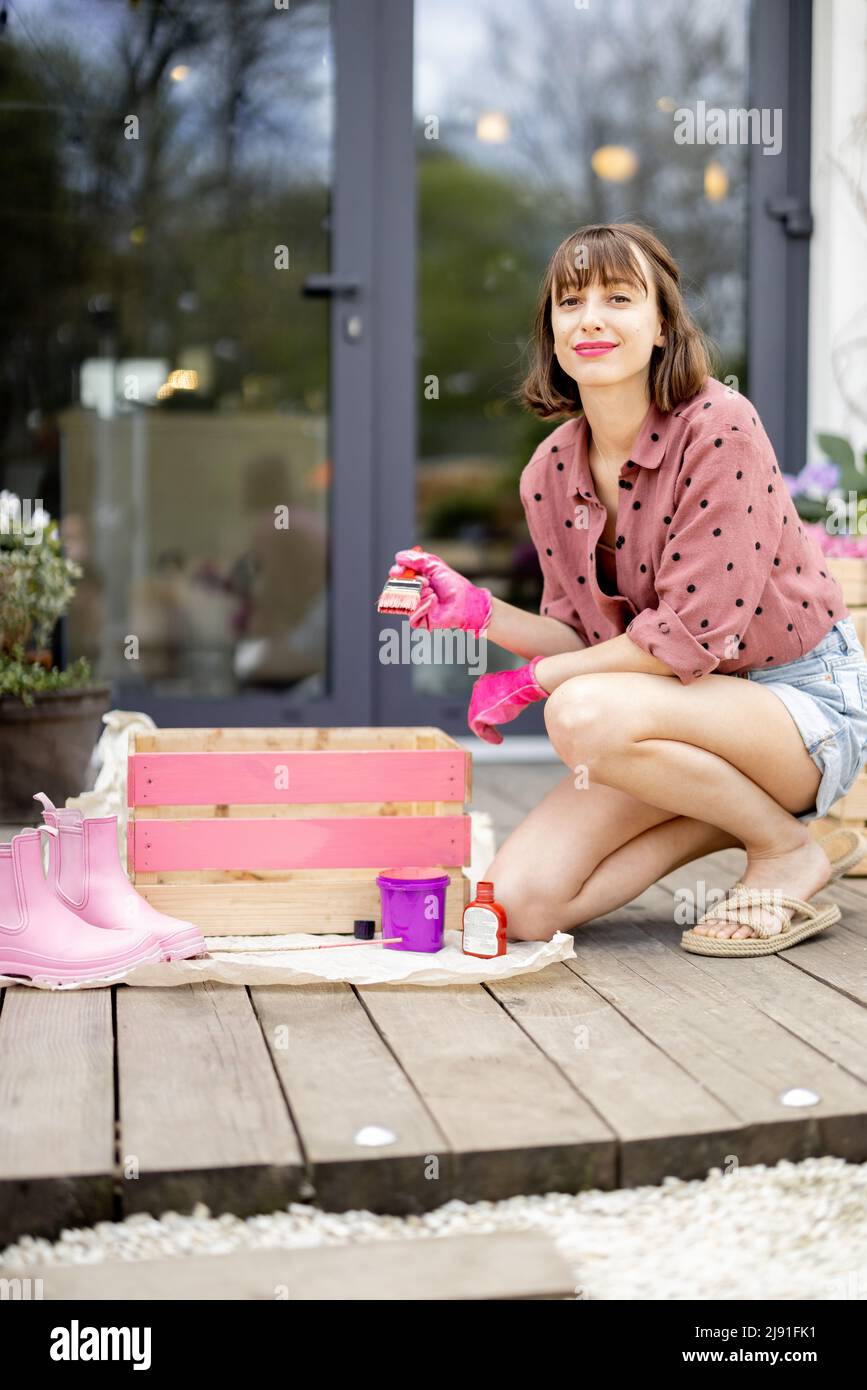 Donna che dipinge scatola di legno, facendo un po 'di lavori domestici ristrutturanti all'aperto Foto Stock