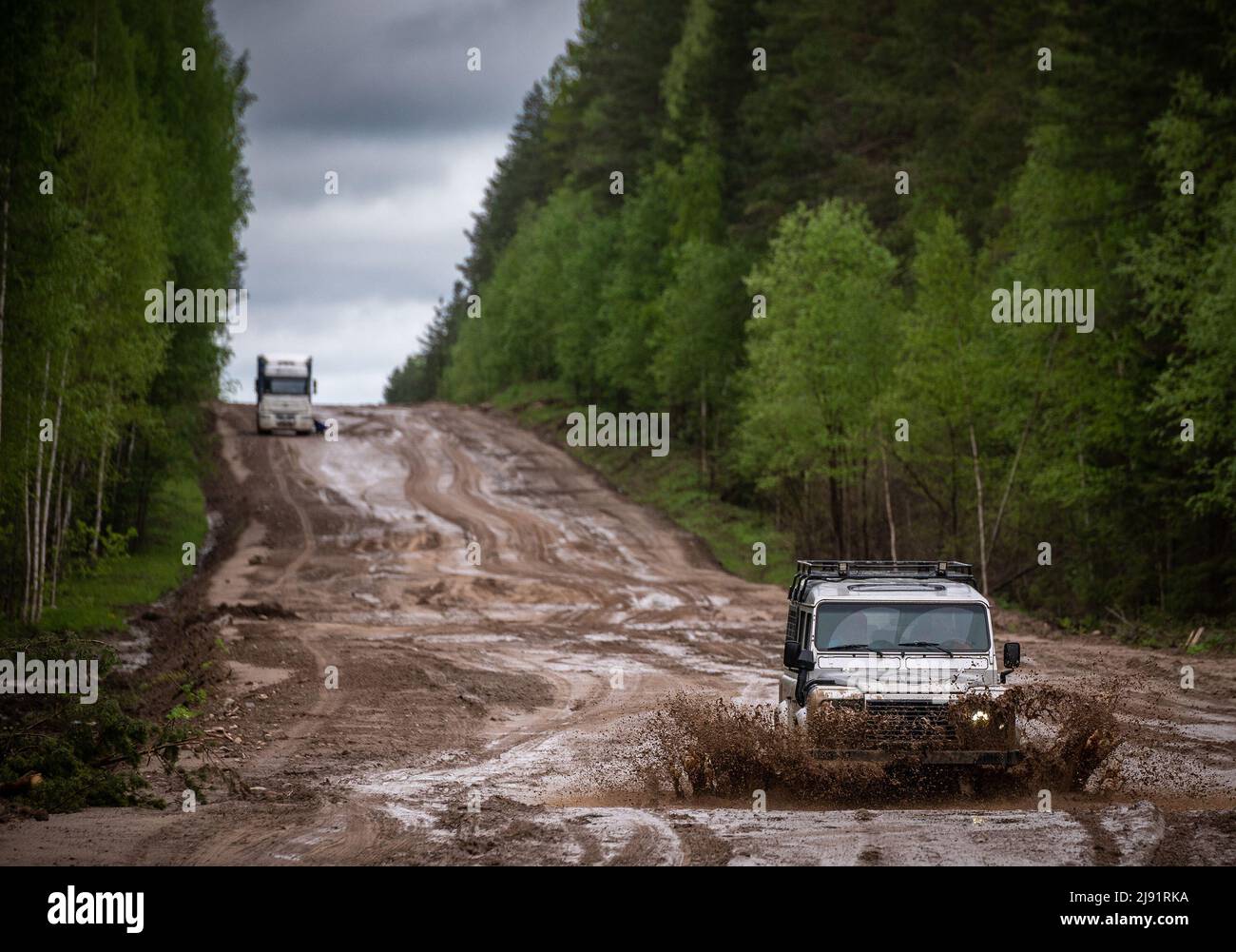 Fuoristrada su strada fangosa in foresta. Spruzzi d'acqua e fango durante la guida fuoristrada Foto Stock