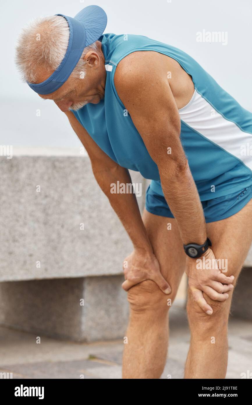 Senior uomo con mancanza di respiro dopo una lunga corsa su distanza colpo verticale Foto Stock