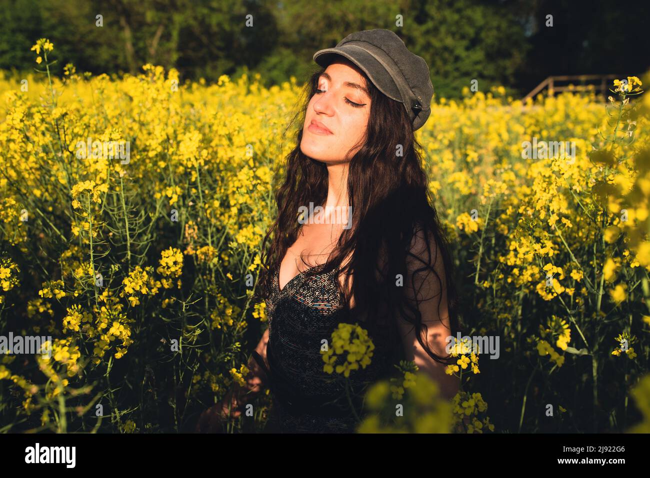 Giovane donna felice e rilassata in un campo di colza di fiori gialli. Ora legale. Foto Stock