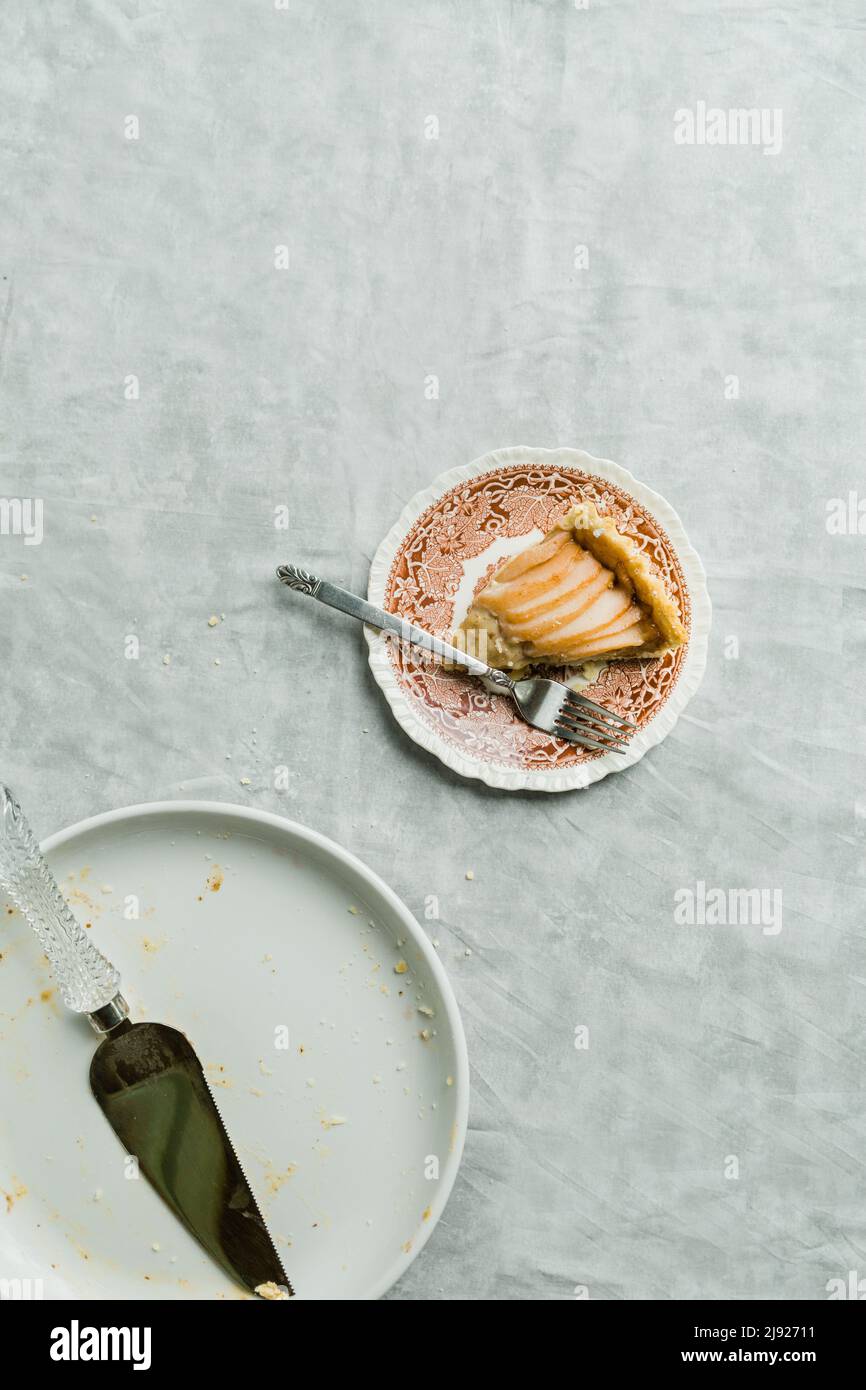 Crostata di pera su sfondo di marmo grigio con mandorle sparse, zucchero e cannella per un dessert autunnale Foto Stock