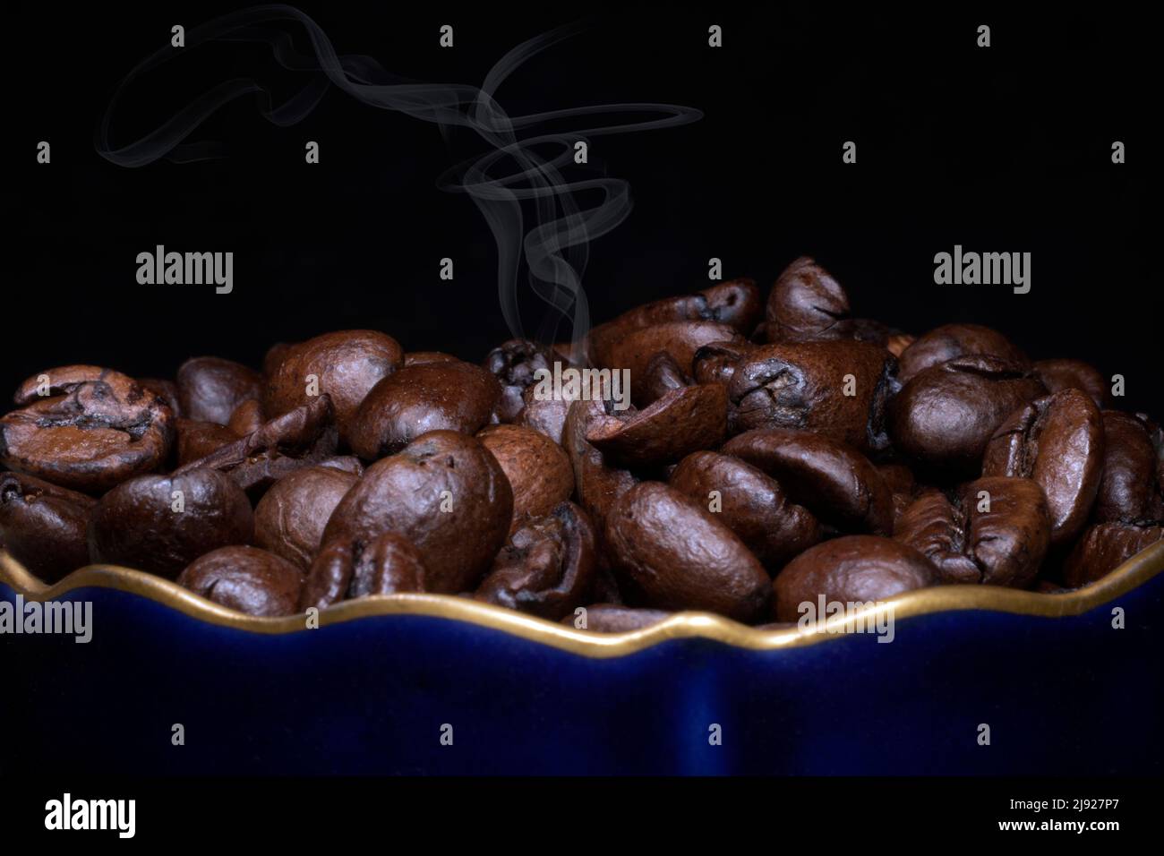 Caffè arrosto di varietà arabica in una tazza di porcellana in blu cobalto con bordo d'oro, fotografia studio con sfondo nero Foto Stock