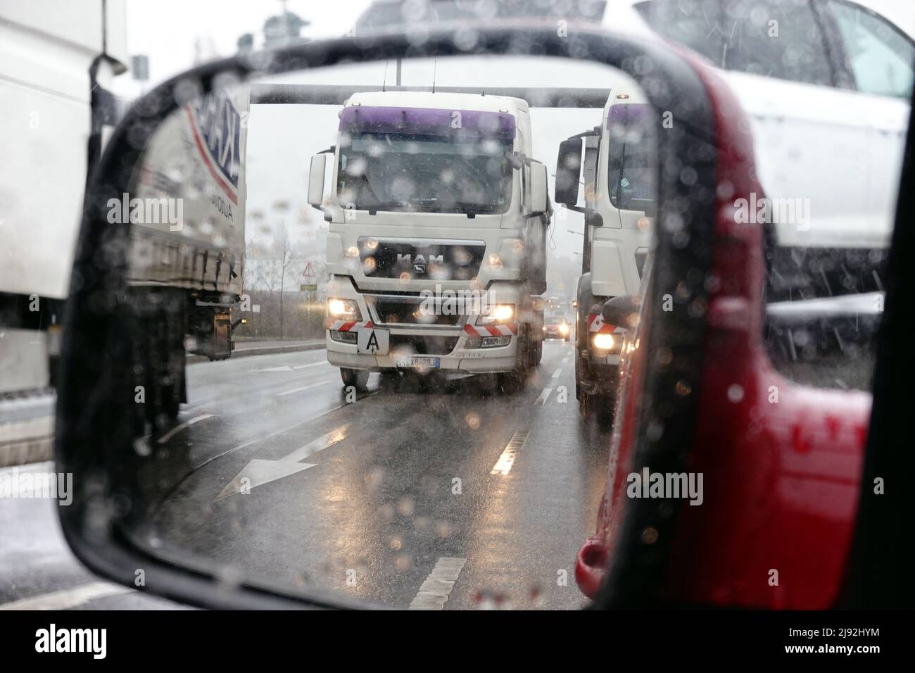 19.03.2021, Berlino, , Germania - i camion si riflettono nello specchietto sinistro di un'auto durante la nevicata. 00S210319D543CAROEX.JPG [VERSIONE MODELLO: NO, PRO Foto Stock
