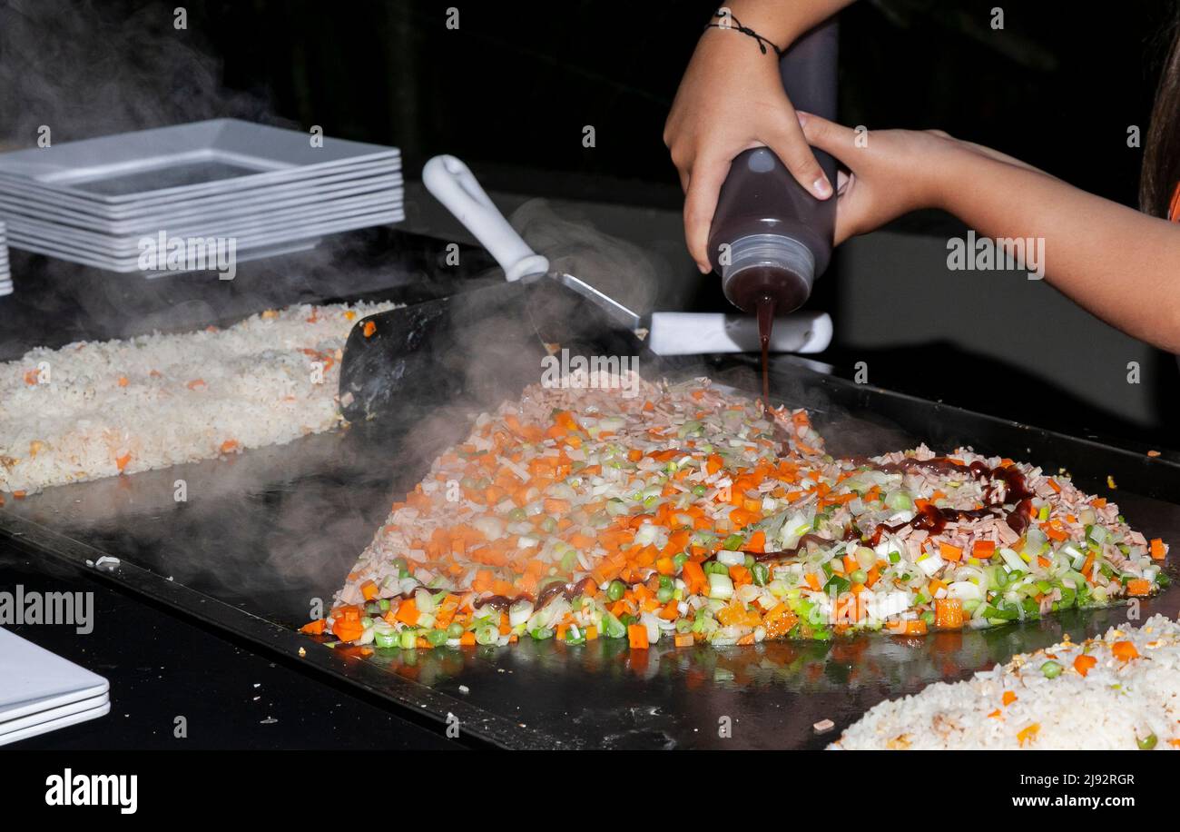 Chef mani cucina cibo su Griddle; riso con verdure Foto Stock
