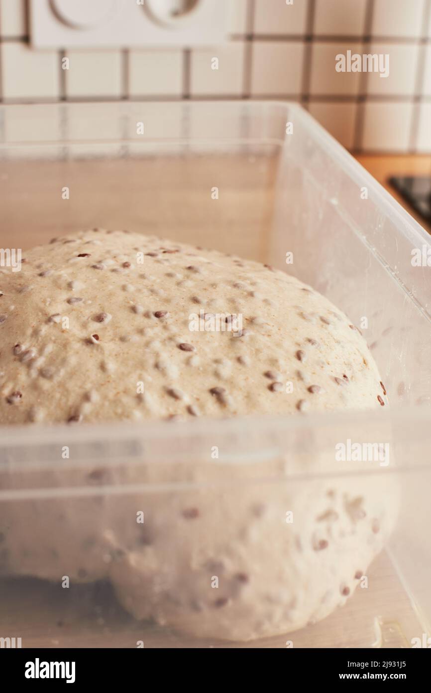 Fare pane di grano fatto in casa con semi di lino. Il risciacquo dell'impasto. Il concetto di pane fatto in casa e cibo sano. Foto verticale. Foto Stock