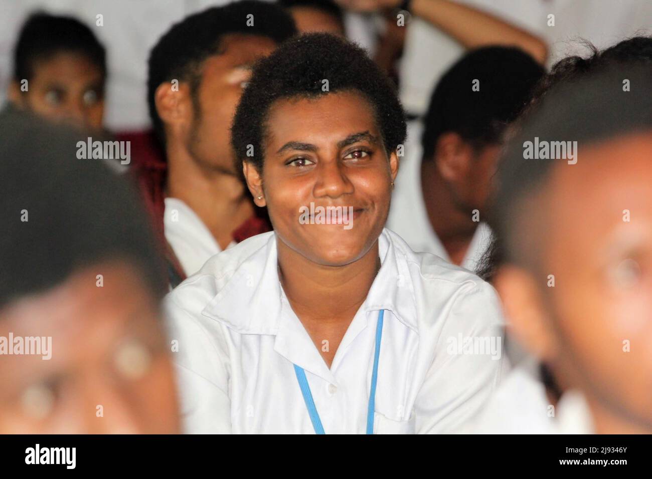 Studente sorridente in camicia bianca a un evento di gruppo, con un cordone blu. Perfetto per l'istruzione, la gioventù e le foto della comunità Foto Stock