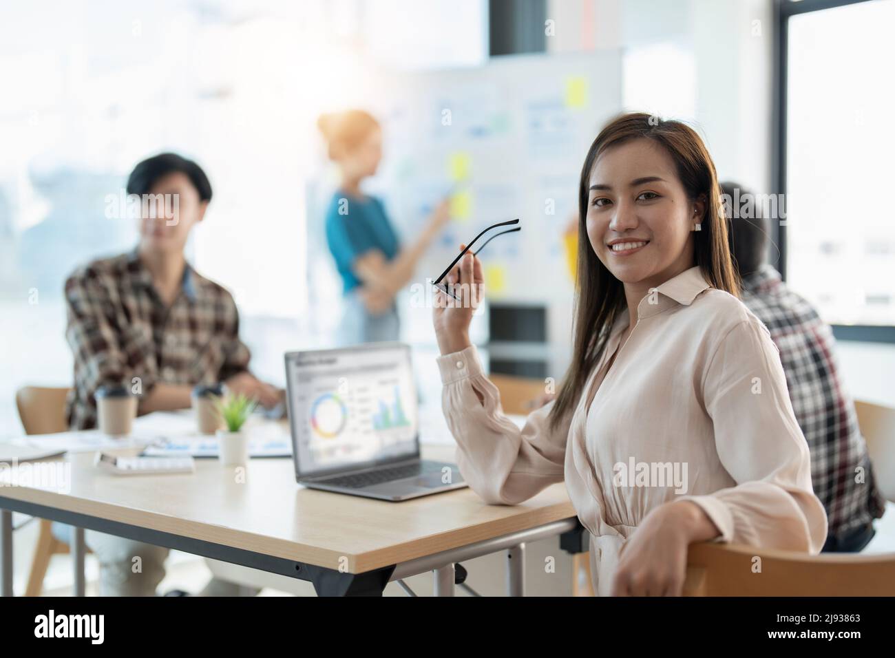Gruppo di giovani uomini d'affari asiatici in abbigliamento casual elegante che lavorano insieme in ufficio creativo utilizzando un laptop. Foto Stock