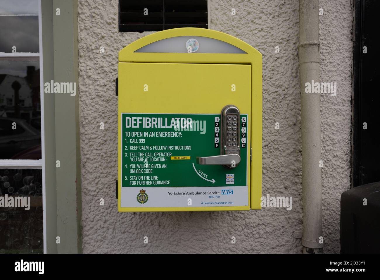 Primo piano della scatola gialla del defibrillatore su una parete a Knaresborough Yorkshire, Regno Unito Foto Stock