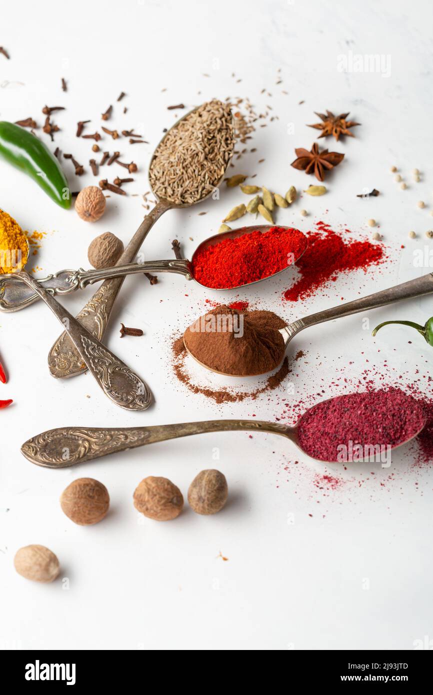 Primo piano di cannella, curry e paprika in polvere spezia su cucchiai di superficie bianca Foto Stock