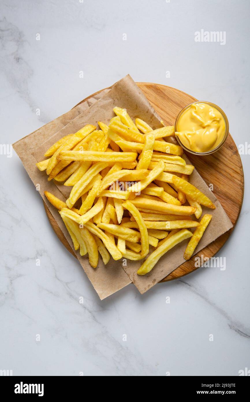 Concetto alimentare patate gialle patate patatine fritte dall'alto sul piatto e salsa al formaggio Foto Stock