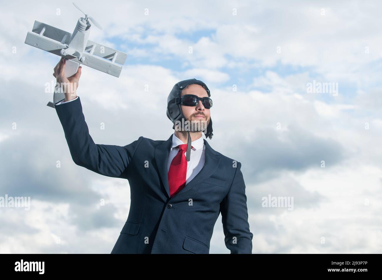 uomo d'affari in abito e cappello pilota lancia giocattolo aereo. realizzazione Foto Stock