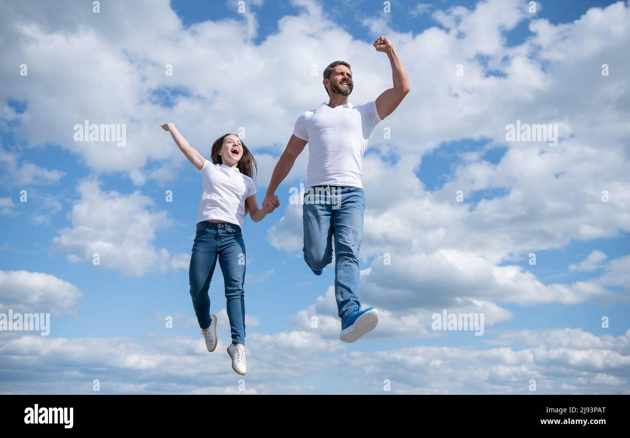 felice padre e figlia saltano nel cielo. luminoso futuro Foto Stock