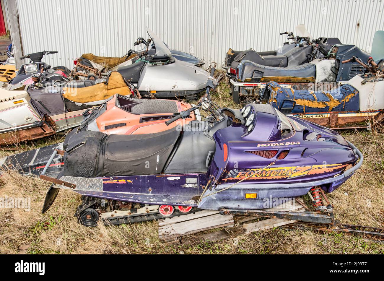 Stykkisholmur, Islanda, 3 maggio 2022: Vecchio, danneggiato, arrugginite o altrimenti obolete motoslitte, parcheggiate in un luogo erboso in un deposito Foto Stock