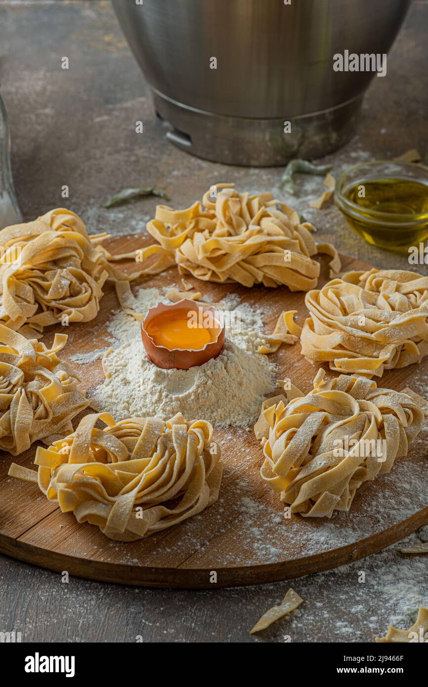 Tagliatelle appena fatte con uova e farina su tavola di legno Foto Stock