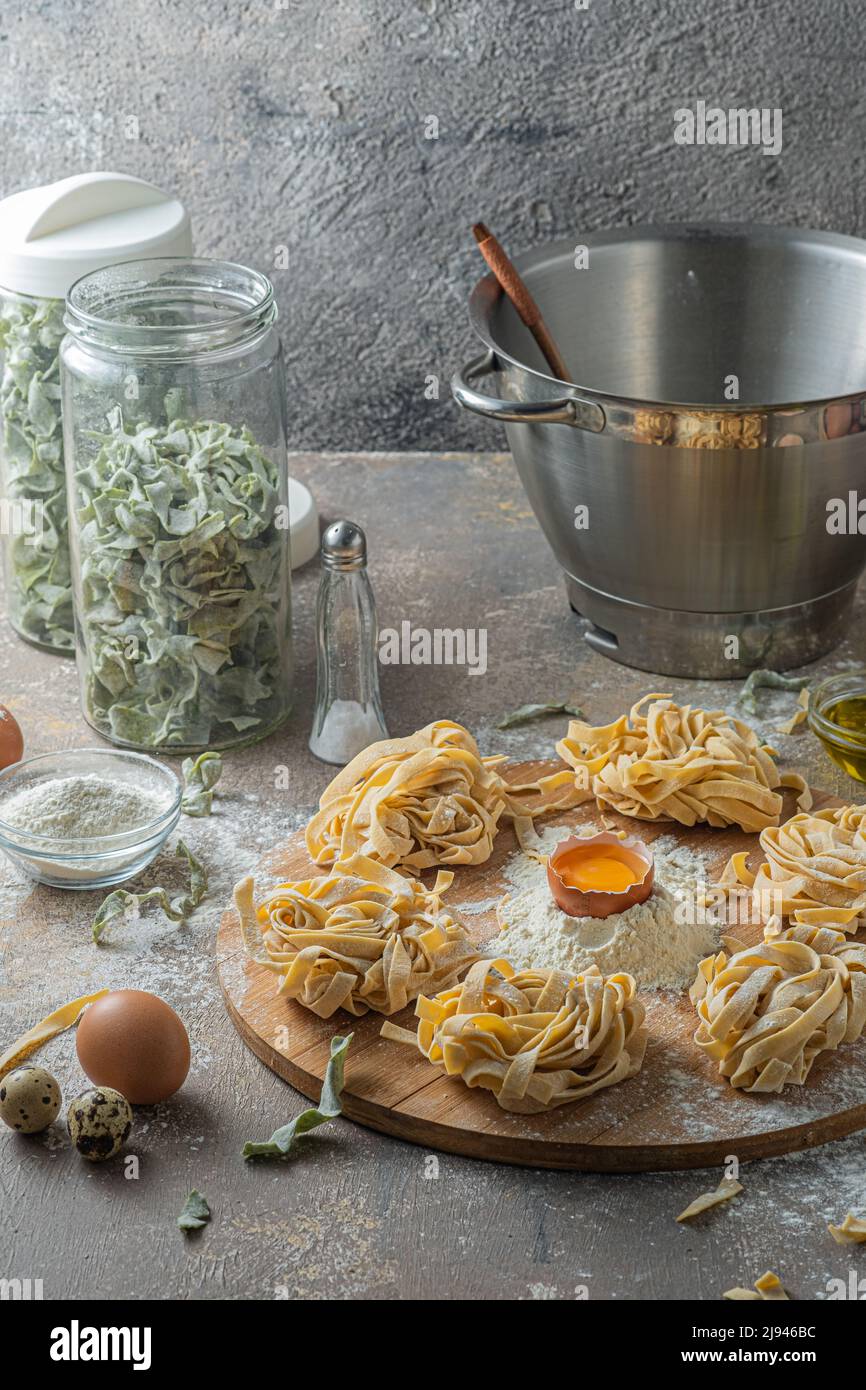 Tagliatelle appena fatte con uova e farina su tavola di legno Foto Stock