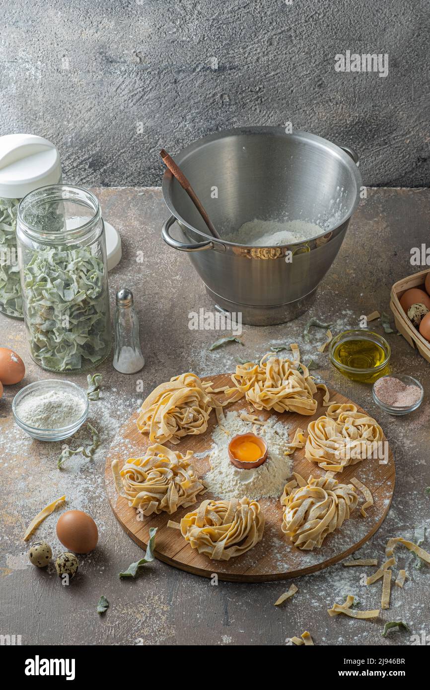 Tagliatelle appena fatte con uova e farina su tavola di legno Foto Stock