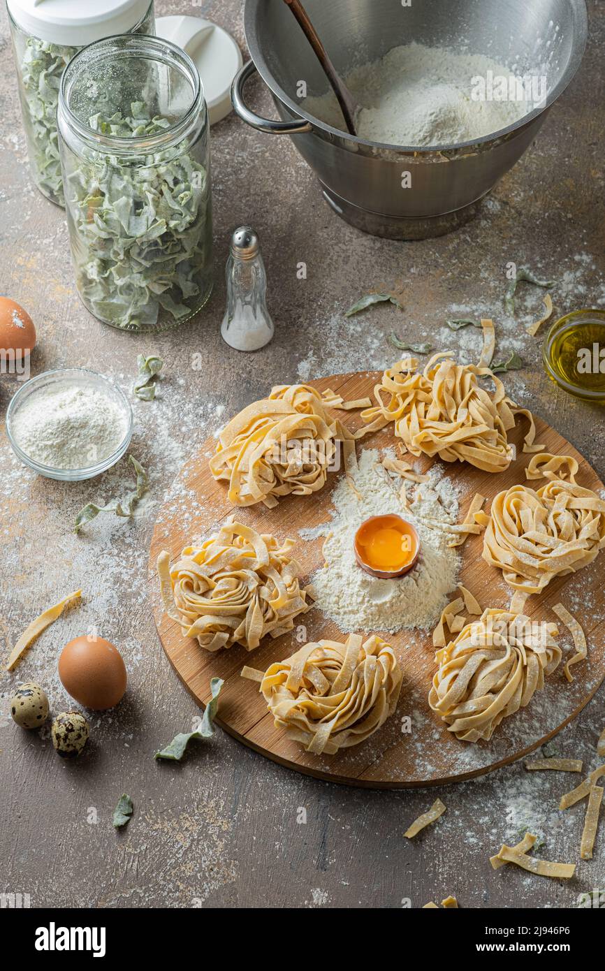 Tagliatelle appena fatte con uova e farina su tavola di legno Foto Stock