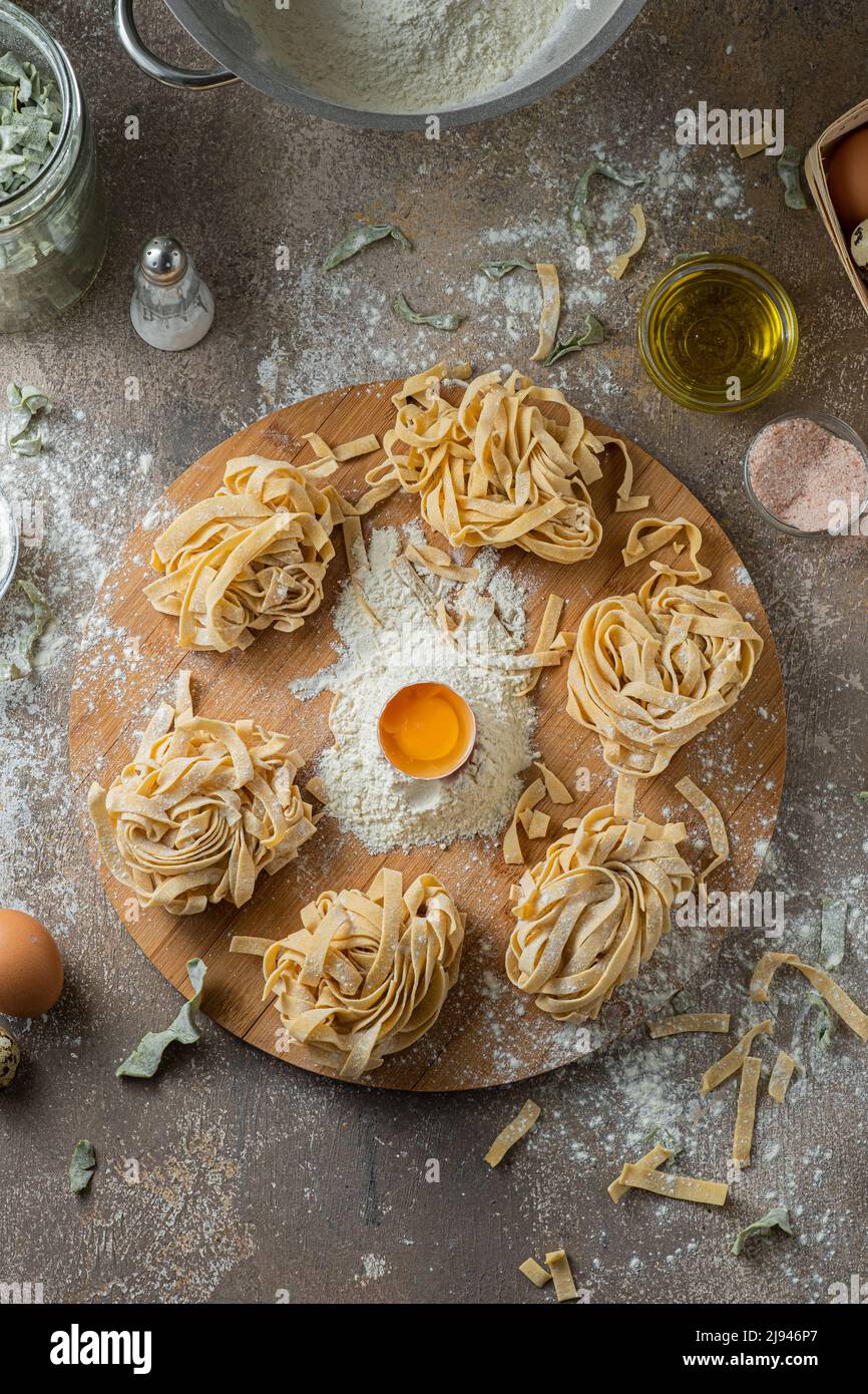 Tagliatelle appena fatte con uova e farina su tavola di legno Foto Stock
