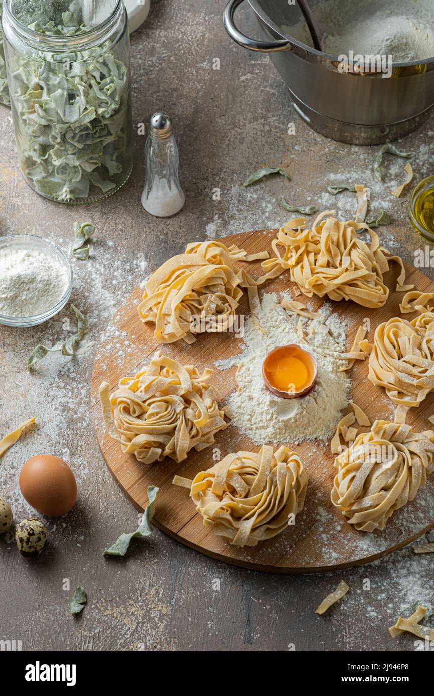 Tagliatelle appena fatte con uova e farina su tavola di legno Foto Stock