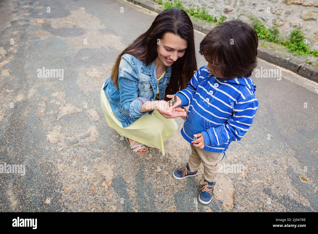 Madre e ragazzo piccolo bello che gioca all'aperto con una lumaca. Foto Stock