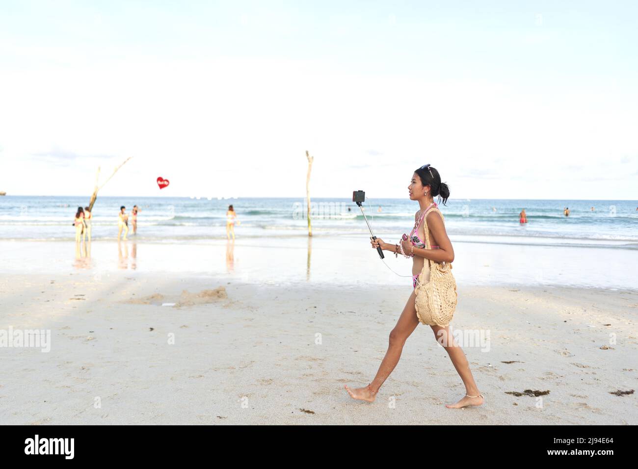 Streamer camminare su una spiaggia mentre fa un flusso dal vivo usando un mobile Foto Stock