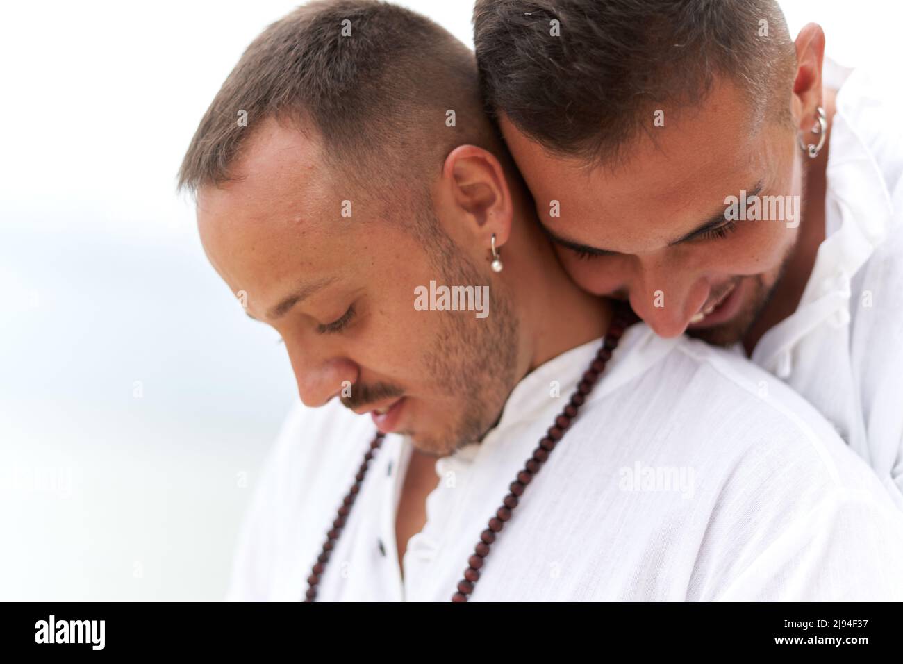 Ritratto di due gay in abiti bianchi abbracciati con tenera espressione Foto Stock